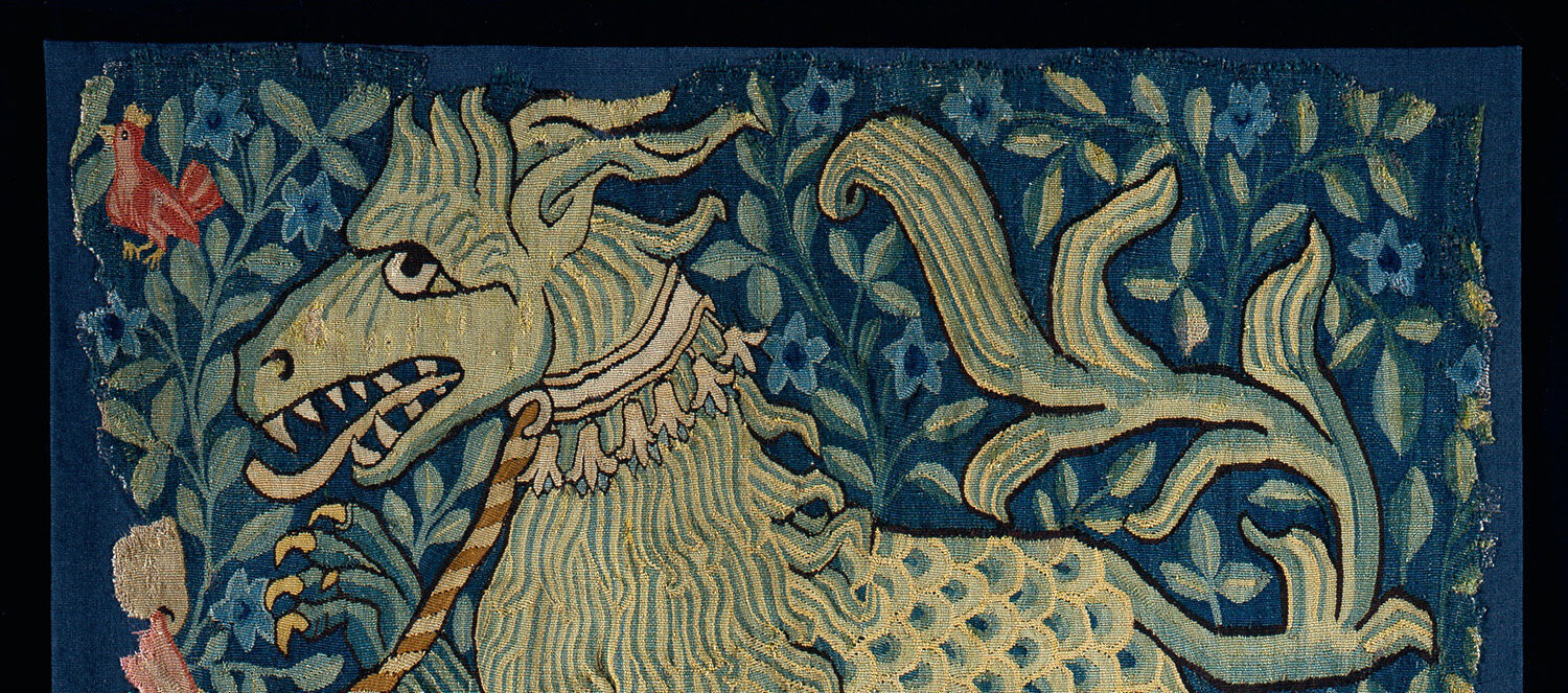 tapestry fragment with dark blue background, plant motifs, and chimeric beast at center